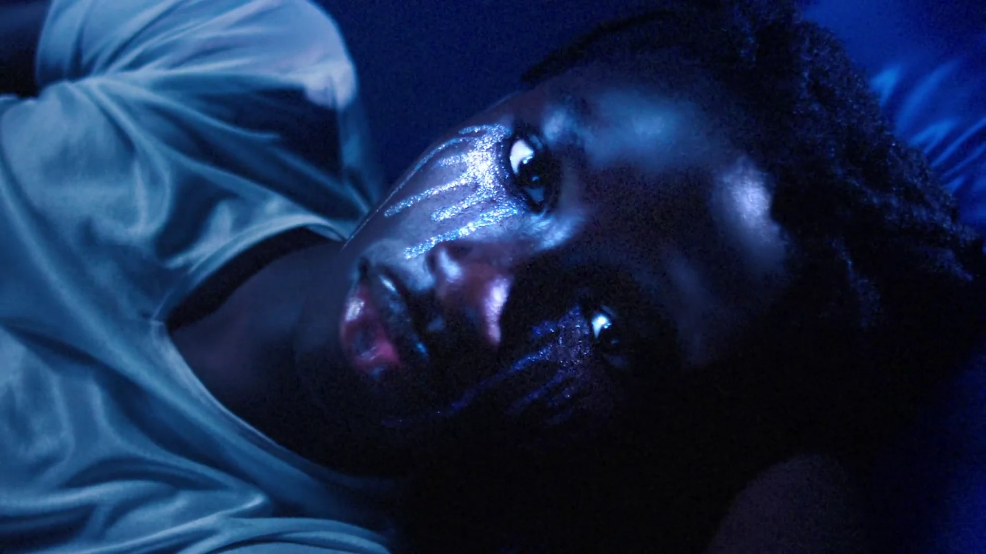 The blue-lit makeup portrait on the bed